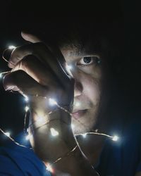 Close-up of man holding lights at night 