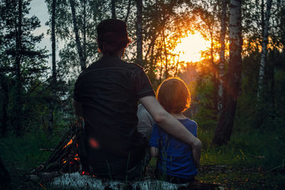 Rear view of two people sitting in the forest