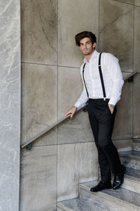Portrait of man wearing suspenders while standing on steps