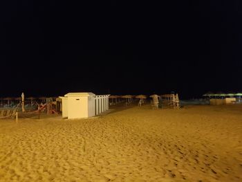 Beach by buildings against clear sky at night