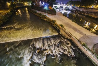 High angle view of river by illuminated city at night