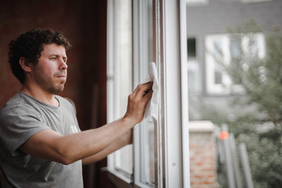 Caucasian man cleans the window frame.