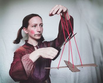 Young woman playing with puppet against textile