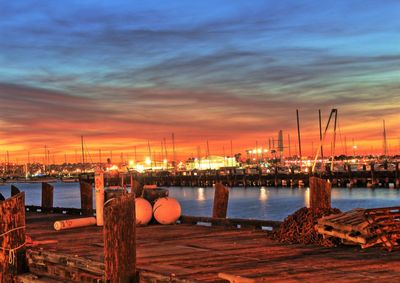 Pier at harbor against cloudy sky during sunset