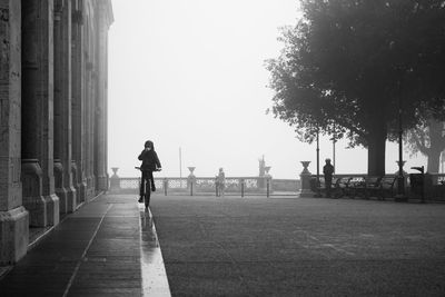 Woman riding bicycle on street against clear sky