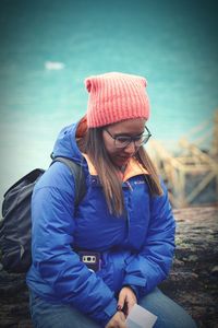 Woman wearing hat sitting in park during winter