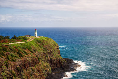 Lighthouse by sea against sky