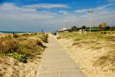 Footpath by sea against sky