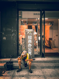 People with text on glass against building in city