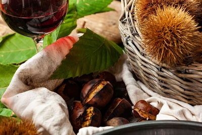 Roasted chestnuts on cloth and a glass of red wine.