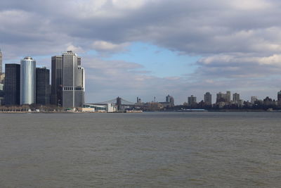 Sea by modern buildings against sky in city