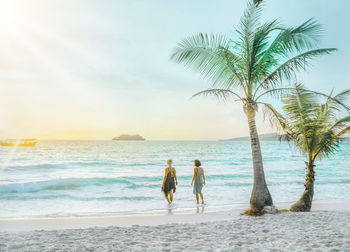 Rear view of people standing on beach against sky