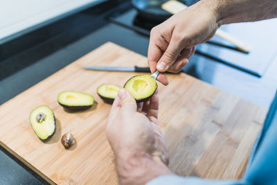 Man cooking in the kitchen in a denim shirt. an anonymous man is cooking avocados