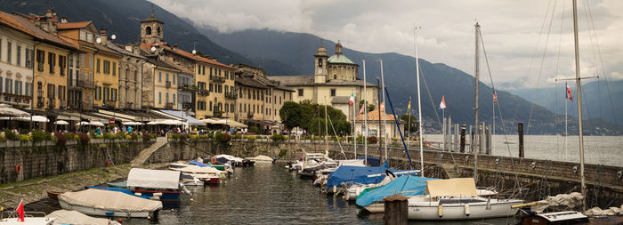 Boats moored at harbor against sky in city