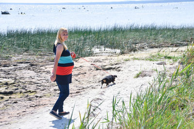 Full length portrait of pregnant woman with dog walking on land