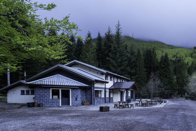 House amidst trees and houses against sky