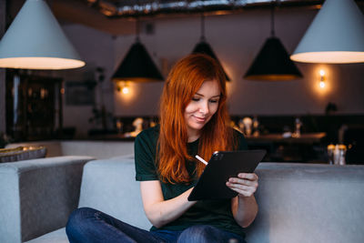 Young woman using mobile phone while sitting in laptop