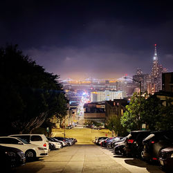 Cars on road by buildings in city at night