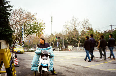 People on street in city against sky