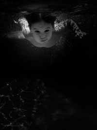 Portrait of shirtless boy swimming in pool at night