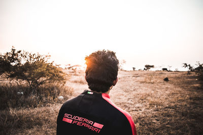 Rear view of man standing on field against clear sky