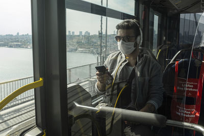 Man wearing mask using mobile phone in train