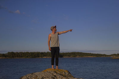 Man standing on rock looking at sea against sky