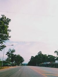 Road by trees against sky