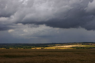 Scenic view of field against storm clouds