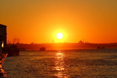 River by suleymaniye mosque in background against orange sky