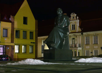 Statue outside house against clear sky at night during winter