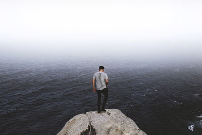 Rear view of man standing on cliff overt seascape