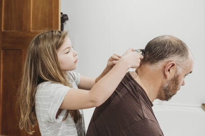 Young girl using electric hair clippers to cut her fathers hair