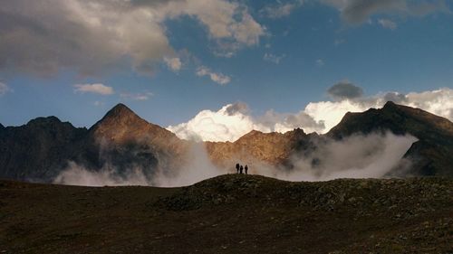 Friends on clouds covering mountains against sky