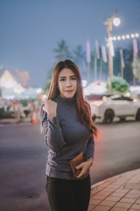 Portrait of beautiful young woman standing in city