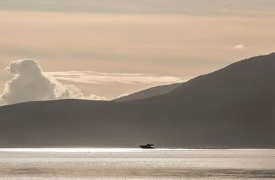 Scenic view of calm sea against mountain range