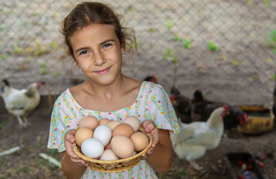 Portrait of cute girl holding eggs in basket