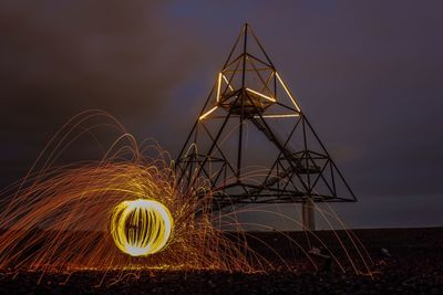 Illuminated ferris wheel on field against sky at night