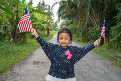 Portrait of girl holding flag in park