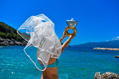 Woman standing by sea against blue sky