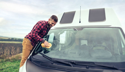 Man cleaning camper van glass outdoor