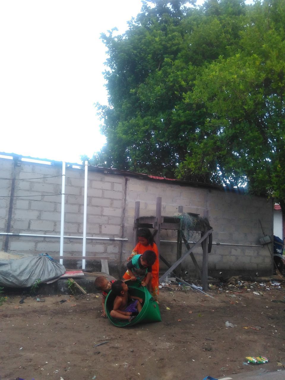 MAN SITTING BY HOUSE AGAINST TREES AND PLANTS