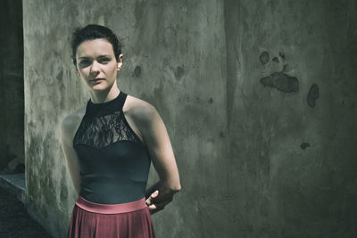 Portrait of young woman standing against wall