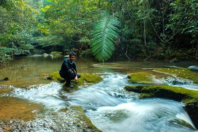 Man in river amidst trees in forest