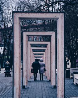 Rear view of people walking on sidewalk by building