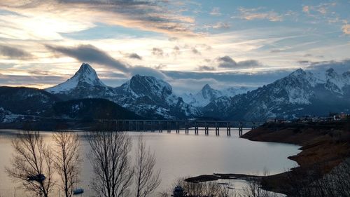 Scenic view of lake and snowcapped mountains against sky during sunset