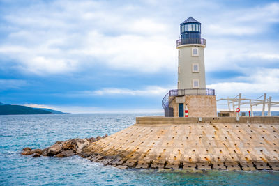 Lighthouse by sea against sky
