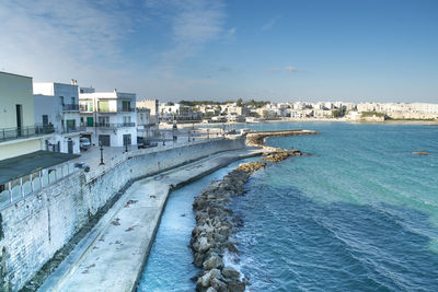 Buildings by sea against sky