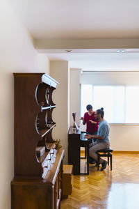 Man and woman using piano at home