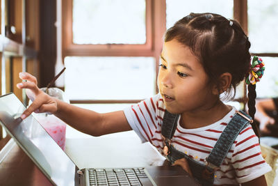 Schoolgirl using touch screen laptop in classroom